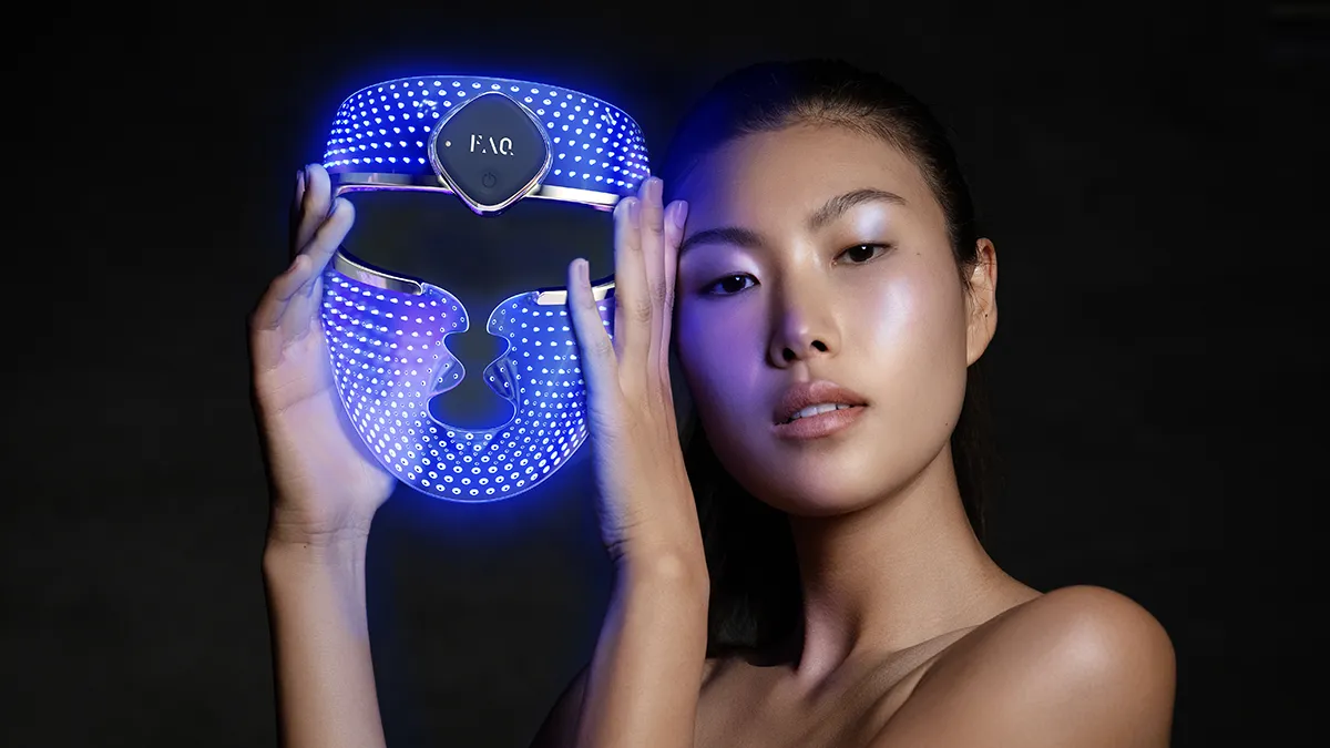 An Asian woman holding FAQ 202 plus blue light led mask
